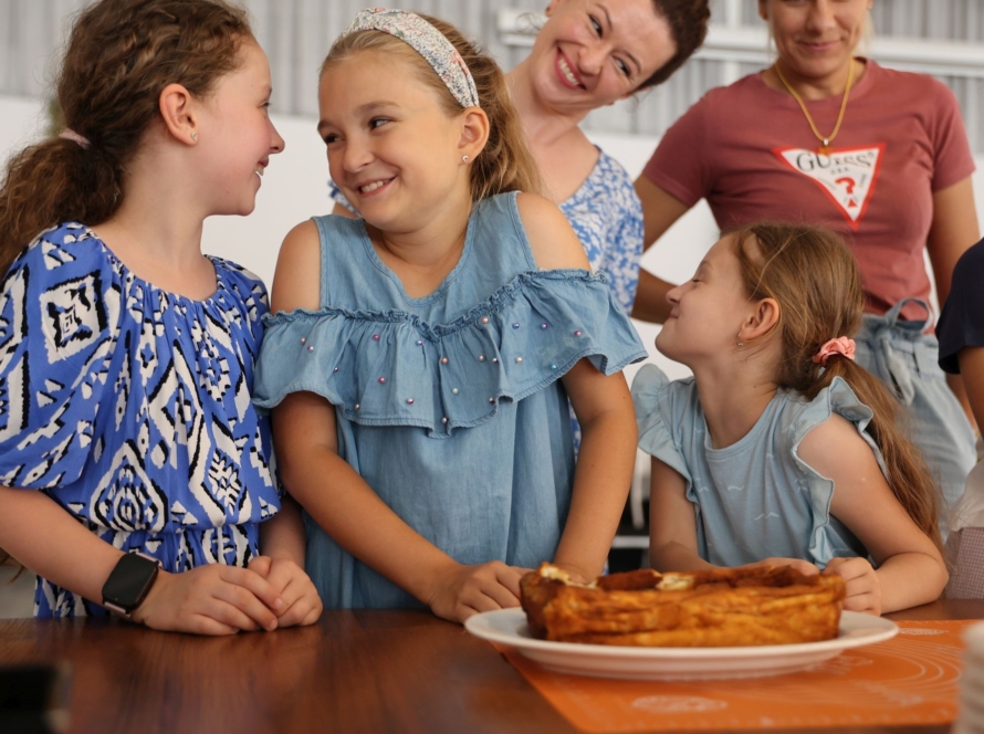 Osoby stojące wokół stołu, na którym leży ciasto